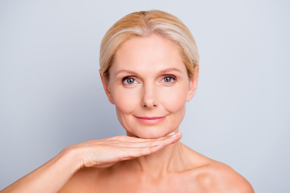 pretty-attractive-charming-woman-demonstrate-show-present-her-perfect-skin-after-peeling-lotion-mask-isolated-on-grey-background-holding-hand-under-chin-treatment-therapy-concept